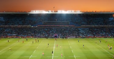 Exciting rugby game unfolding under stunning sunset in large stadium.