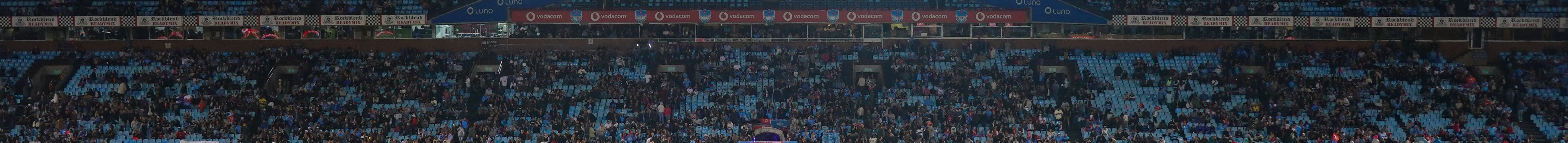 Exciting rugby game unfolding under stunning sunset in large stadium.