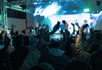 Lively crowd capturing concert moments on smartphones, vibrant lights create dynamic atmosphere.